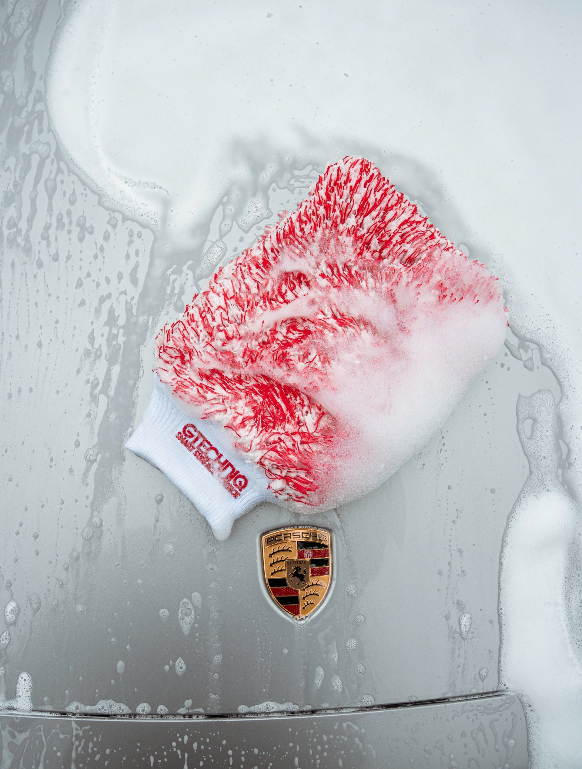A red and white glove is sitting on the side of a porsche car.