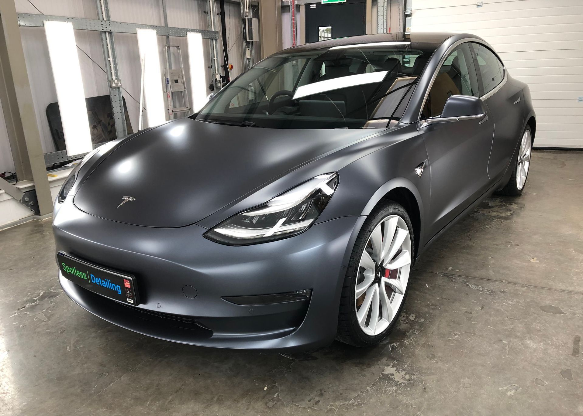 A tesla model 3 is parked in a garage.