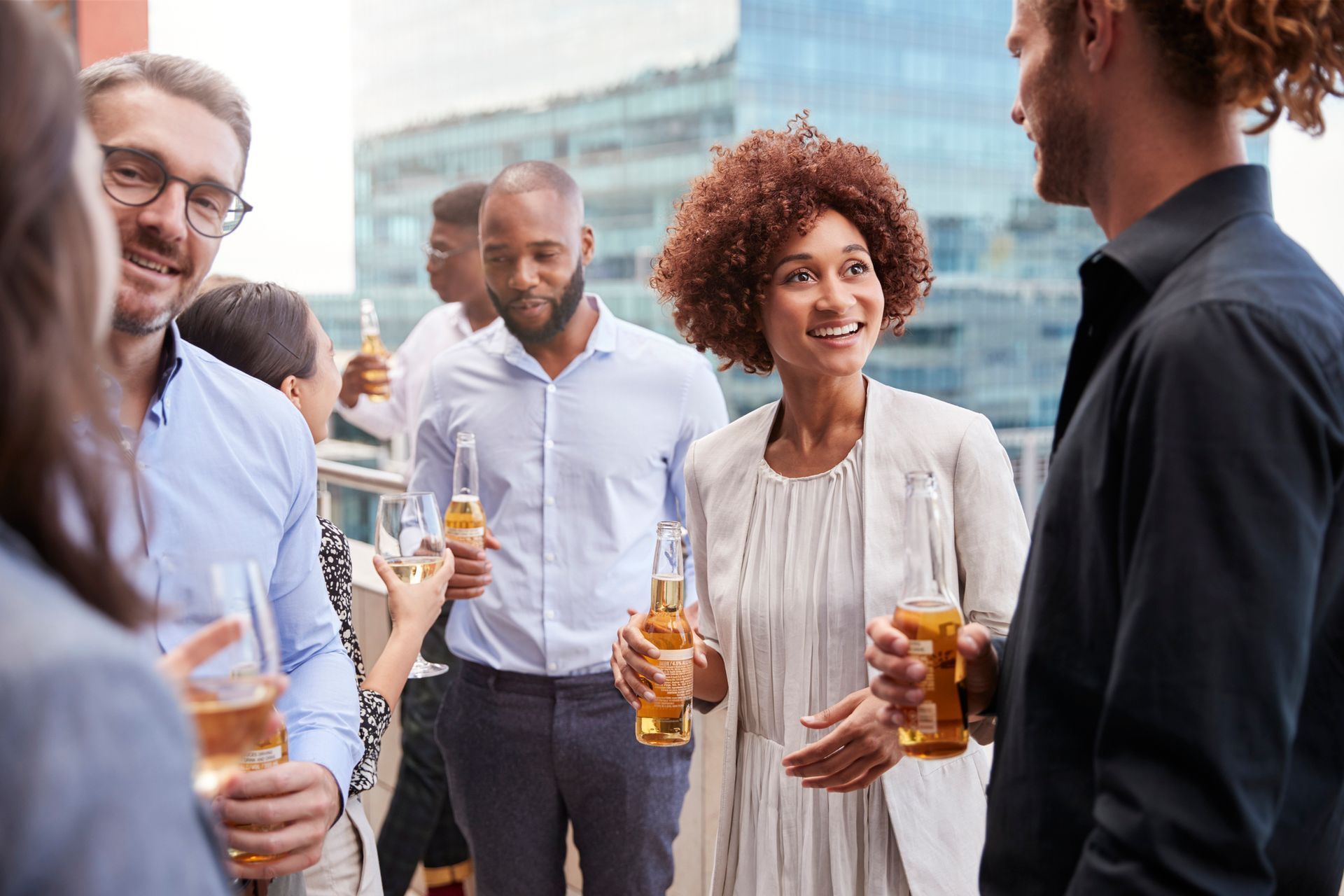 A group of people are standing next to each other holding beer bottles.