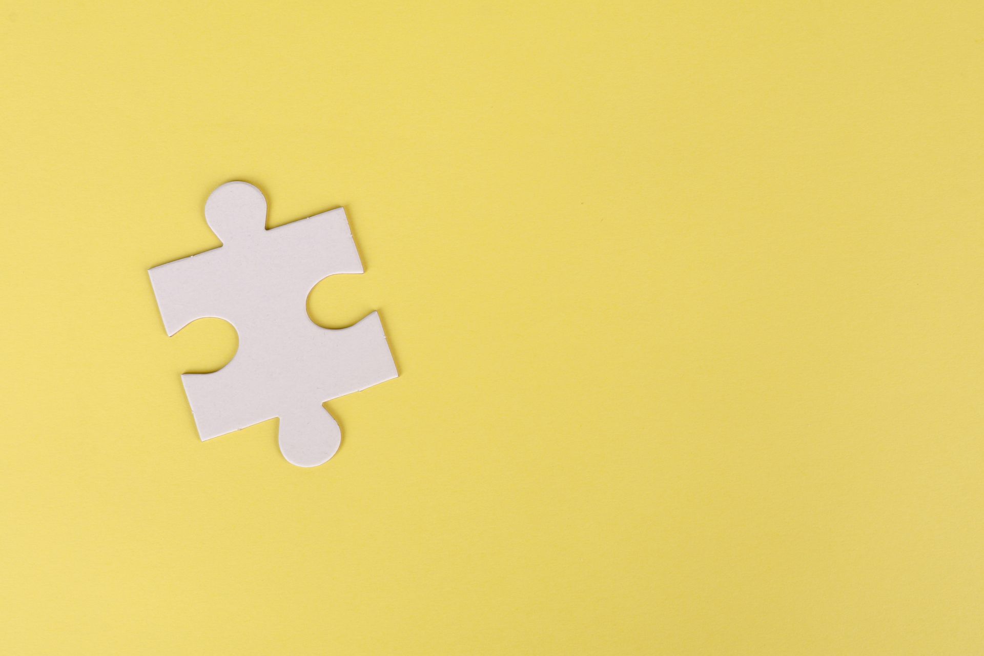 A white puzzle piece on a yellow background.