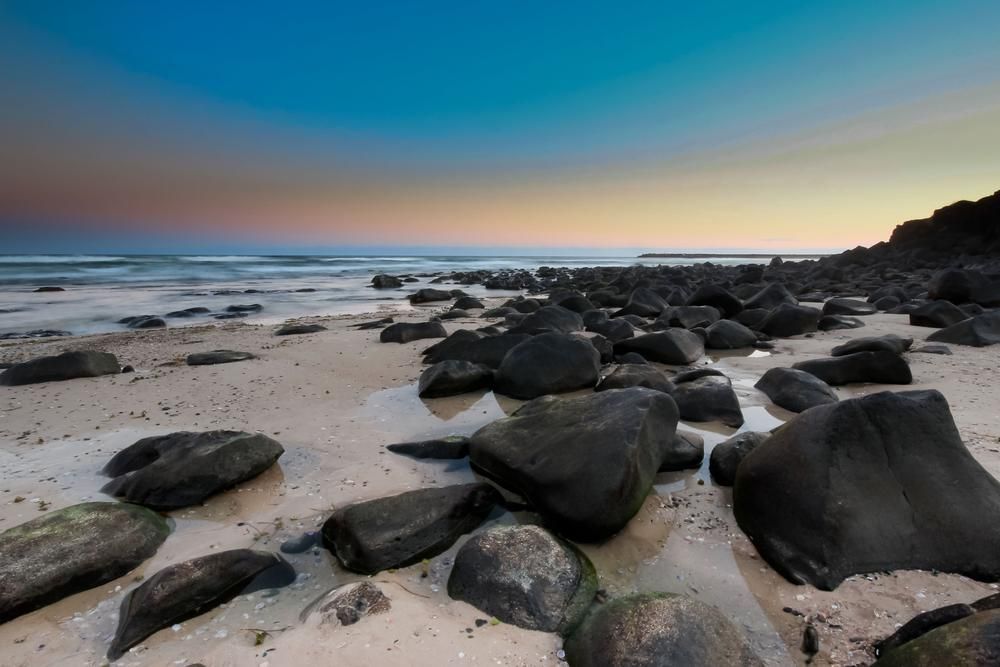 A Rocky Beach with A Sunset in The Background — S & L Sand & Gravel in Ballina, NSW