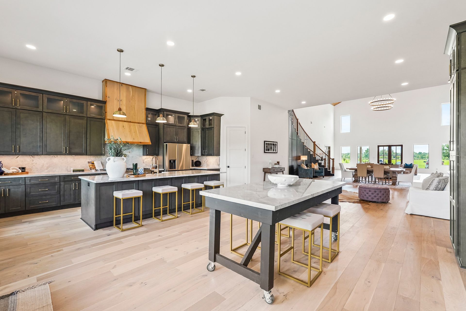 Open-concept kitchen with dark cabinets, large island with stools, and light wood floors. Open-concept kitchen with dark cabinets, large island with stools, and light wood floors.