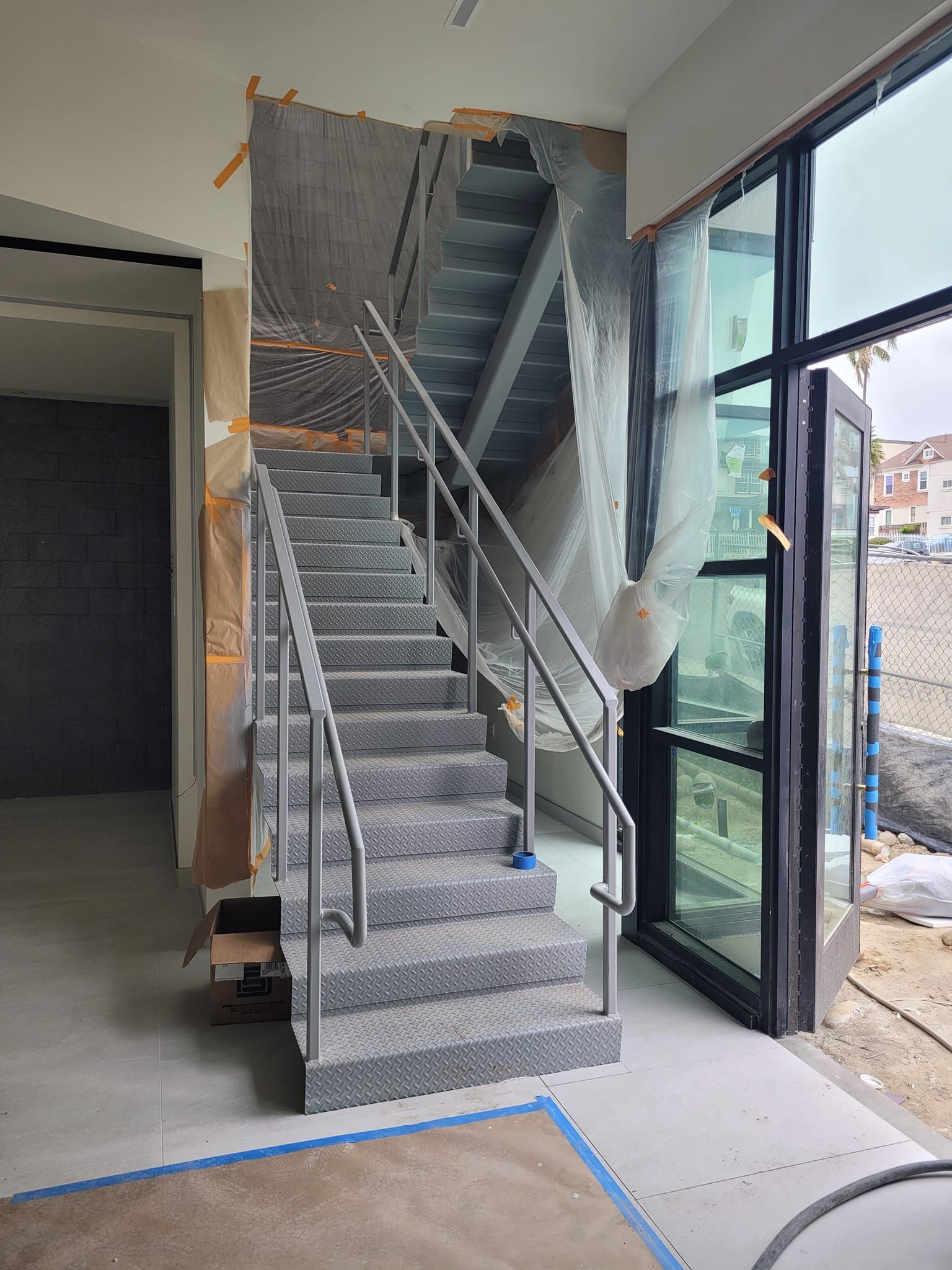 A staircase in a building under construction with a stainless steel railing.