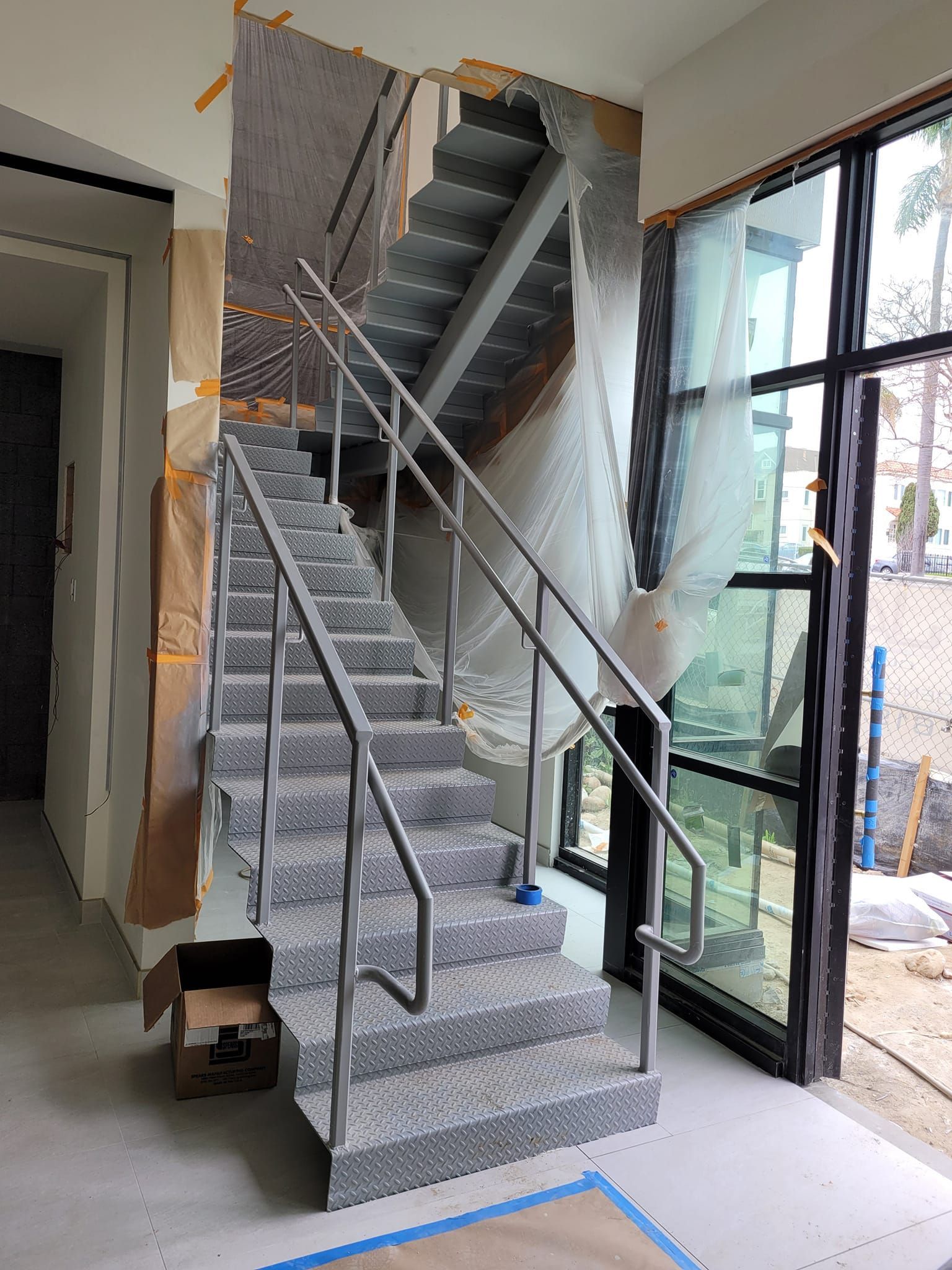 A staircase in a building under construction with a stainless steel railing.