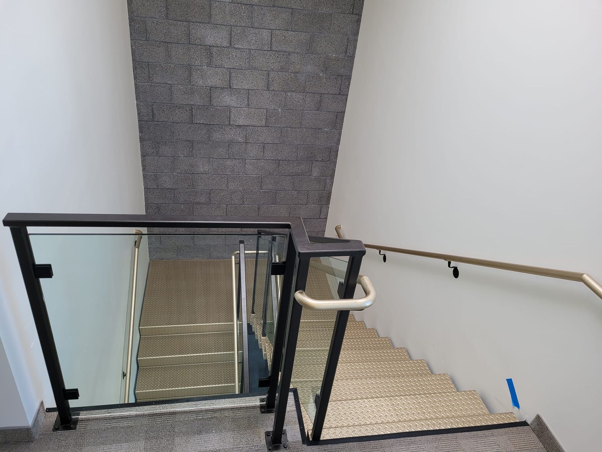 A staircase with a glass railing and a brick wall