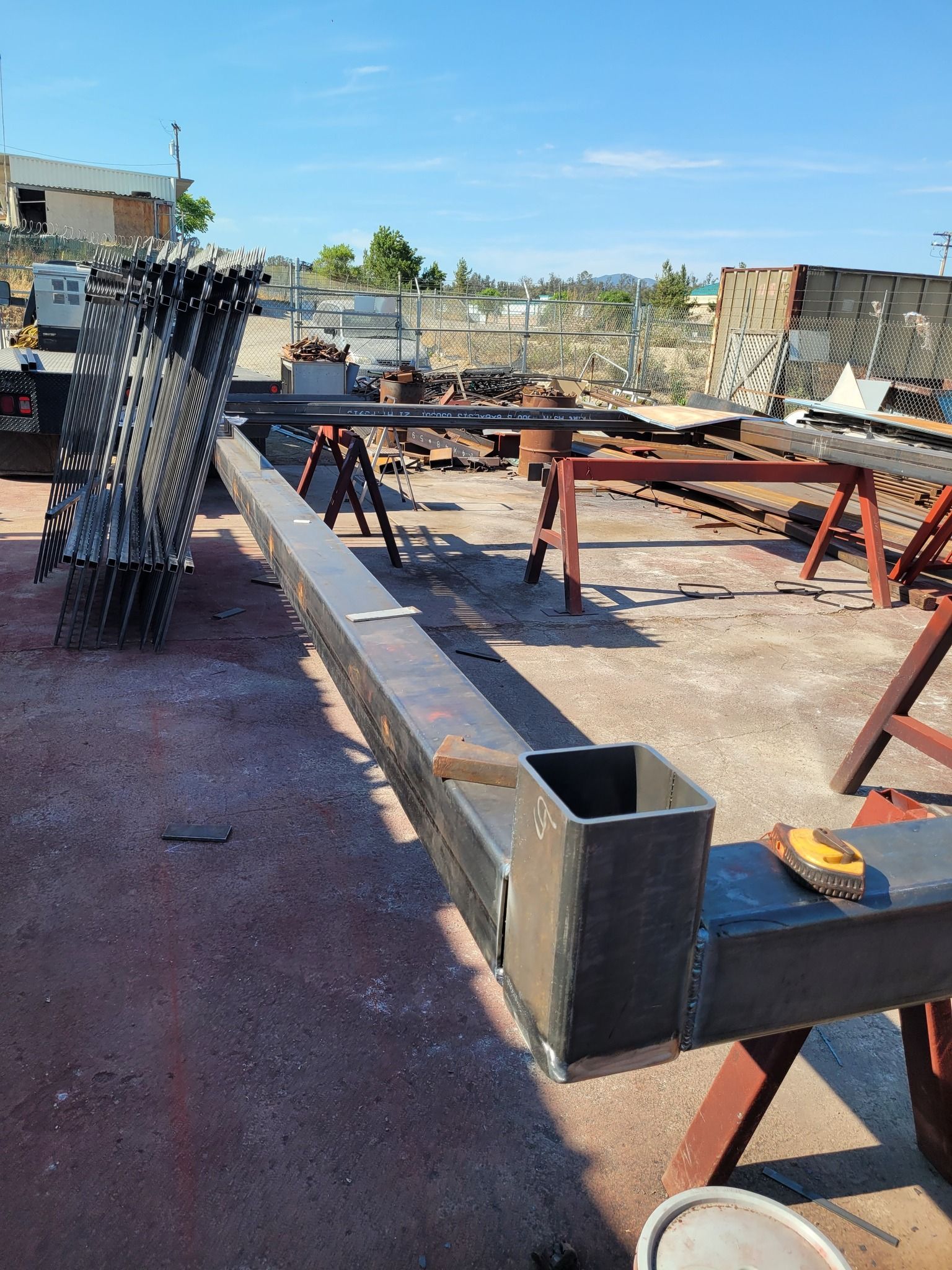A large piece of metal is sitting on top of a wooden table in a yard.
