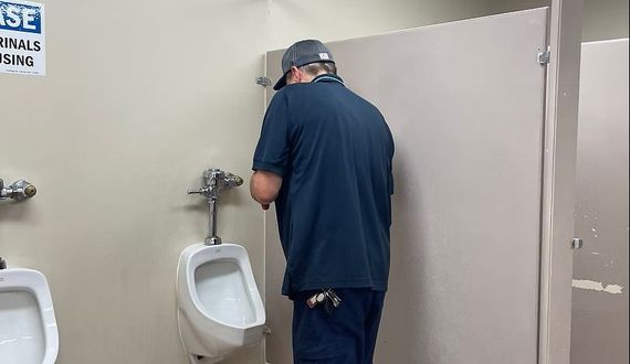 Electrician working on a circuit breaker panel in a residential setting.