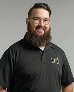Smiling bearded man in black polo shirt with logo on a gray background