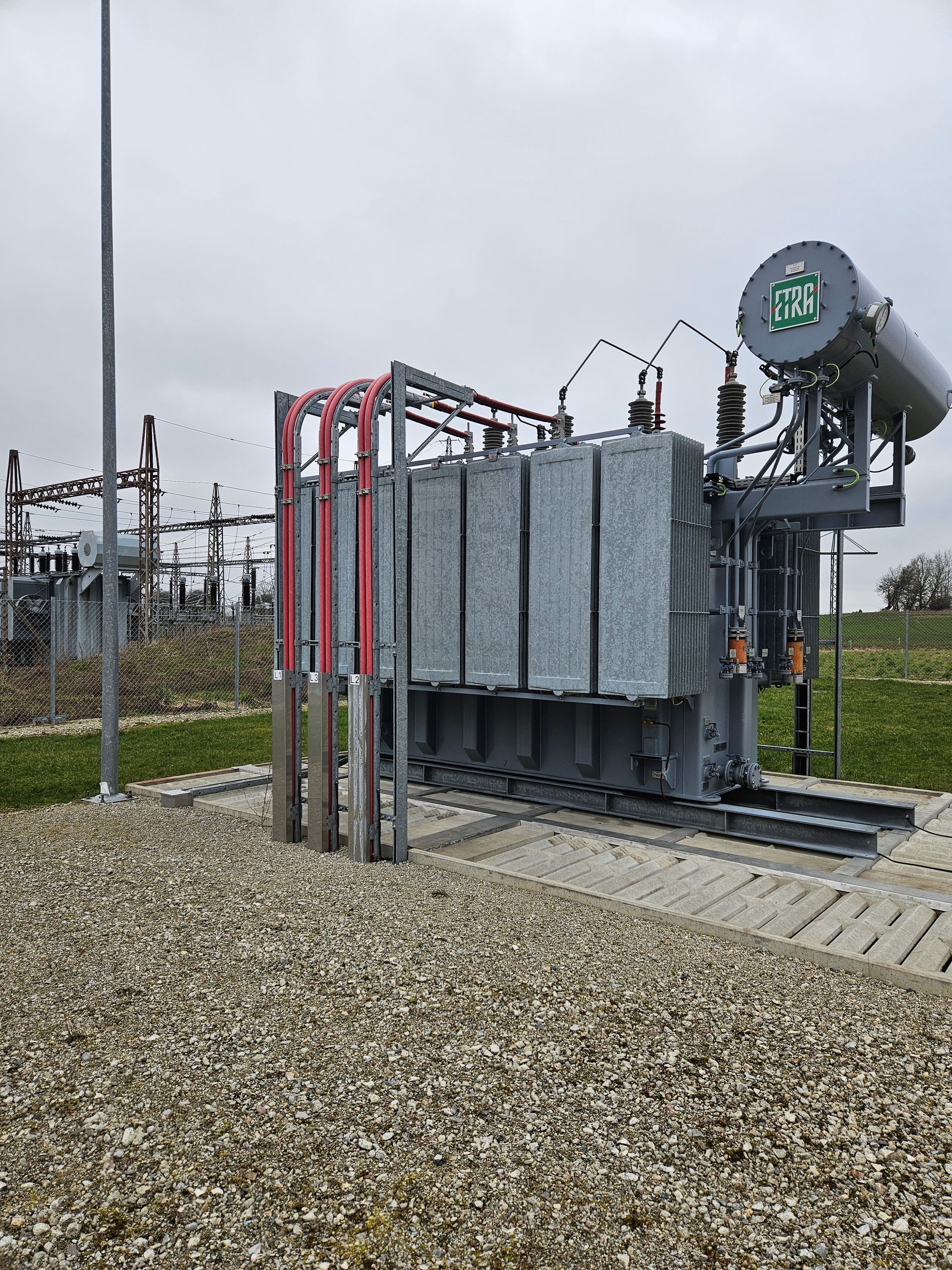 En stor transformer står midt på en grusmark.