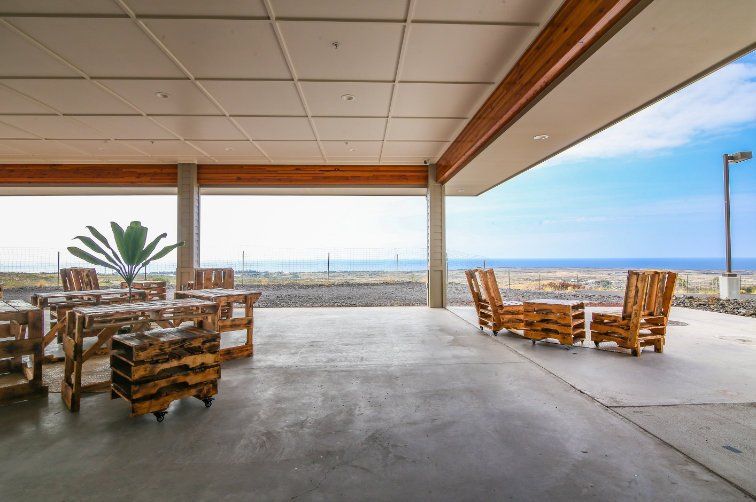A patio with tables and chairs and a view of the ocean.