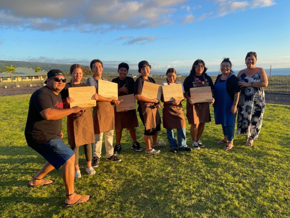 a group of people are standing in a grassy field holding wooden boards .
