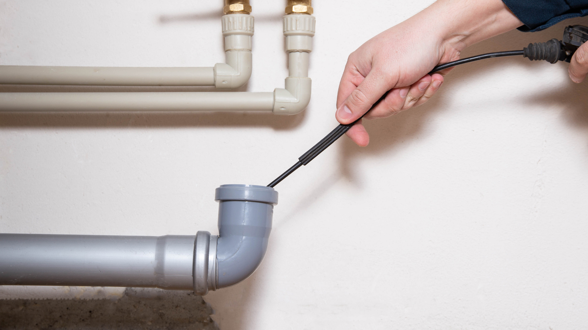 A man is cleaning a drain with a hose.