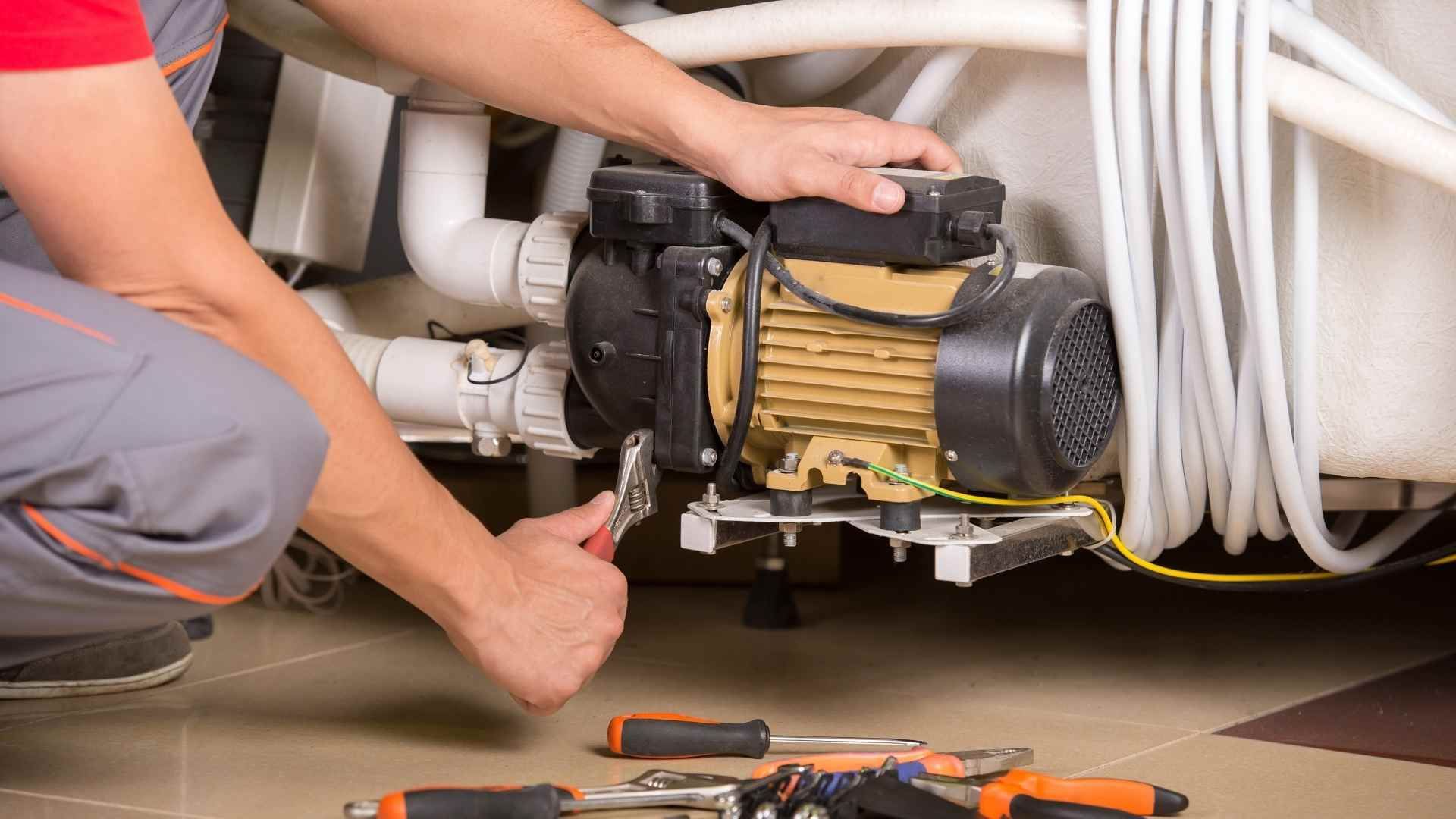 A man is fixing a water pump in a bathroom.