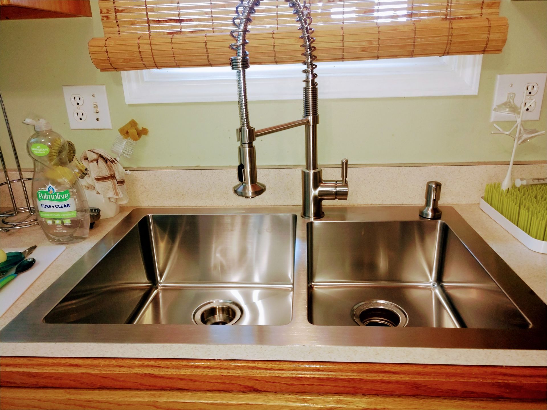 A stainless steel kitchen sink with a soap dispenser on the counter
