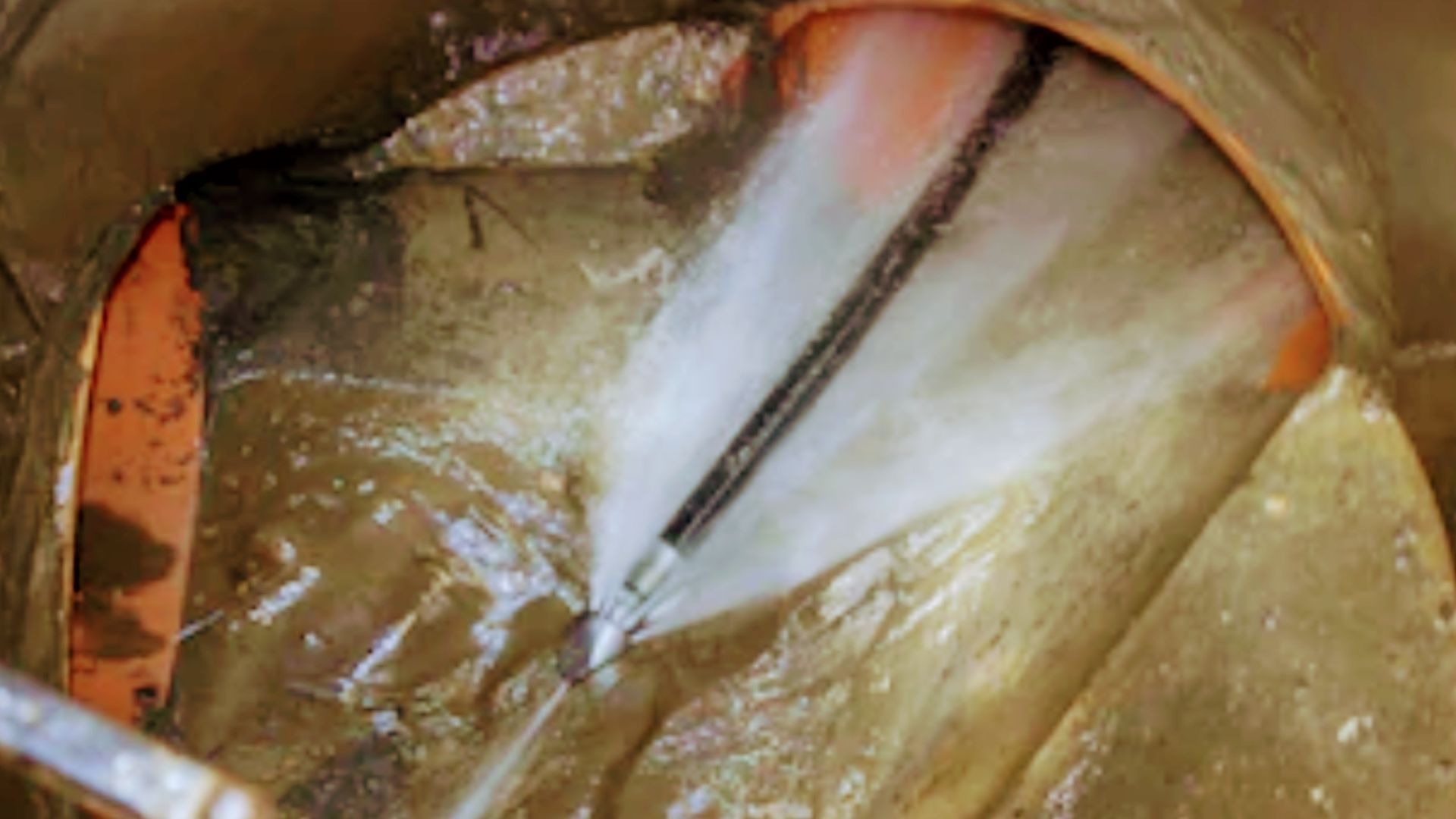 A person is cleaning a pipe with a high pressure washer.