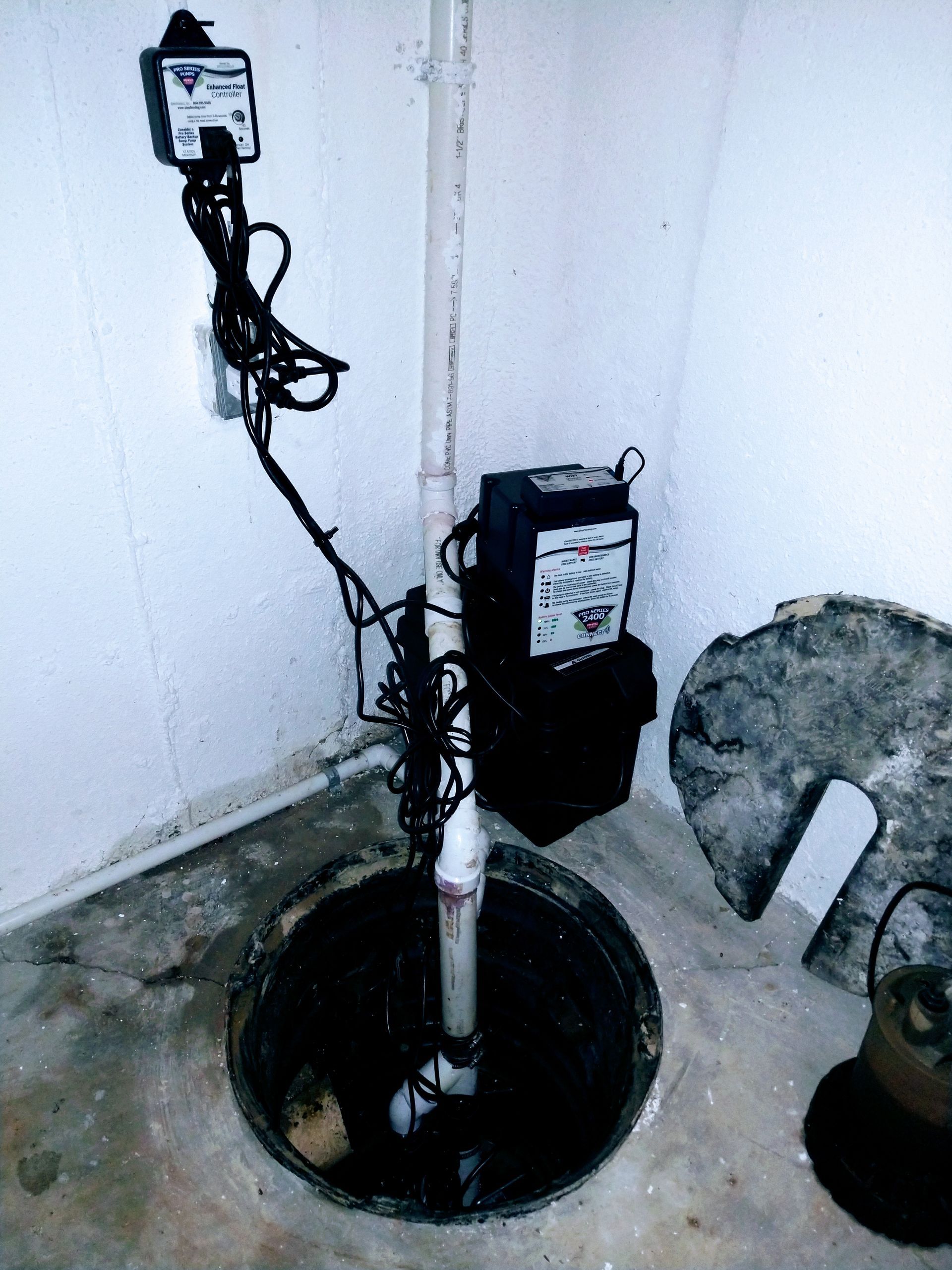 A sump pump is sitting in the corner of a room