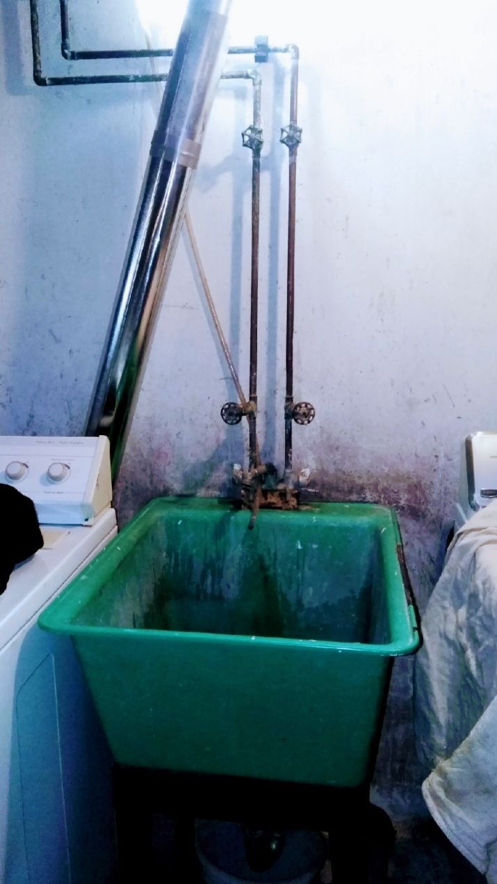 A green sink is in a laundry room next to a washer and dryer.