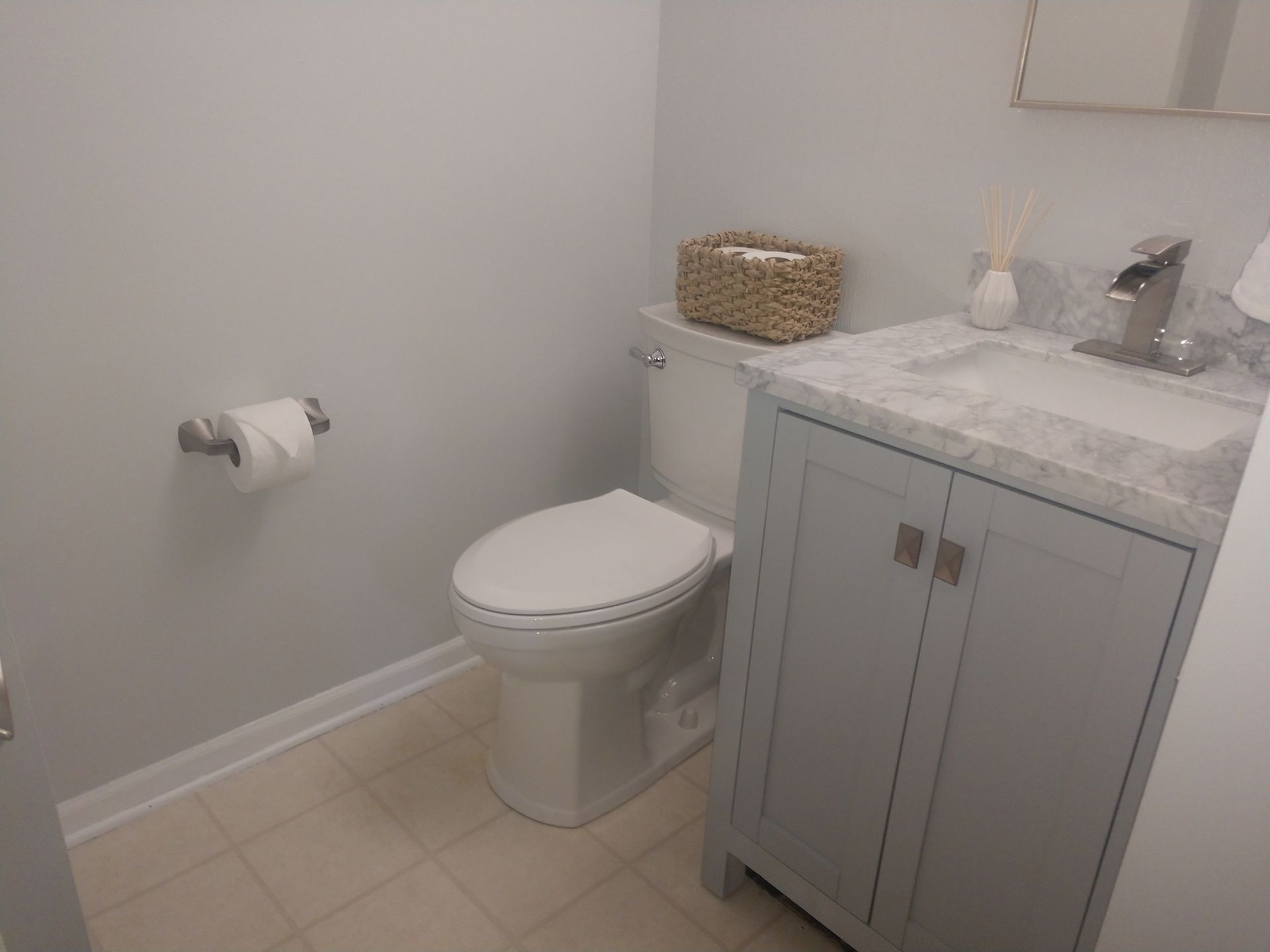 A bathroom with a toilet , sink , and cabinet.