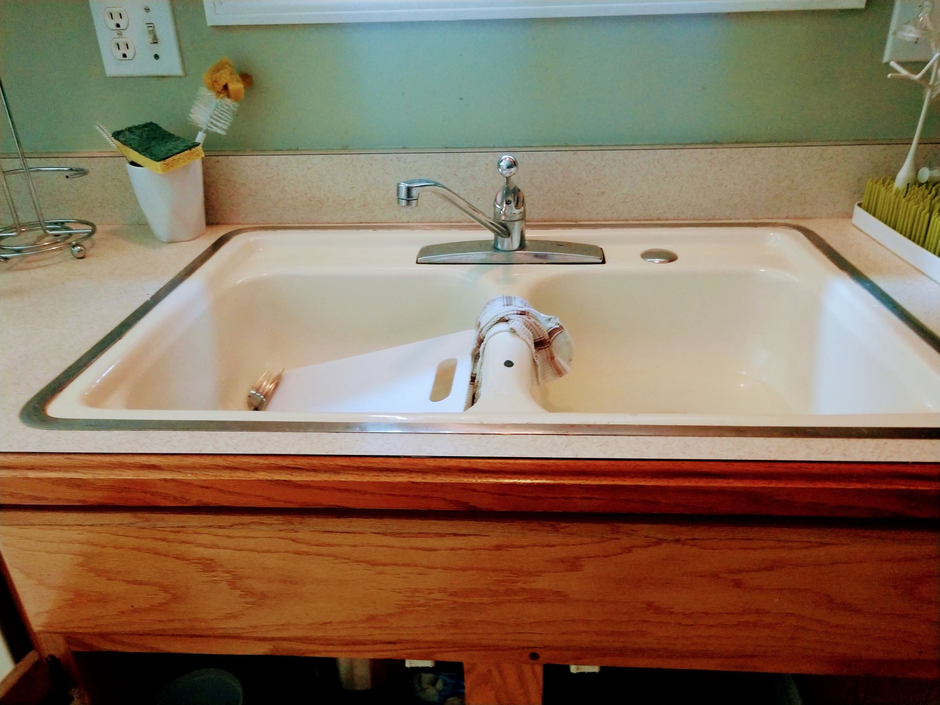 A kitchen sink with a towel hanging out of it