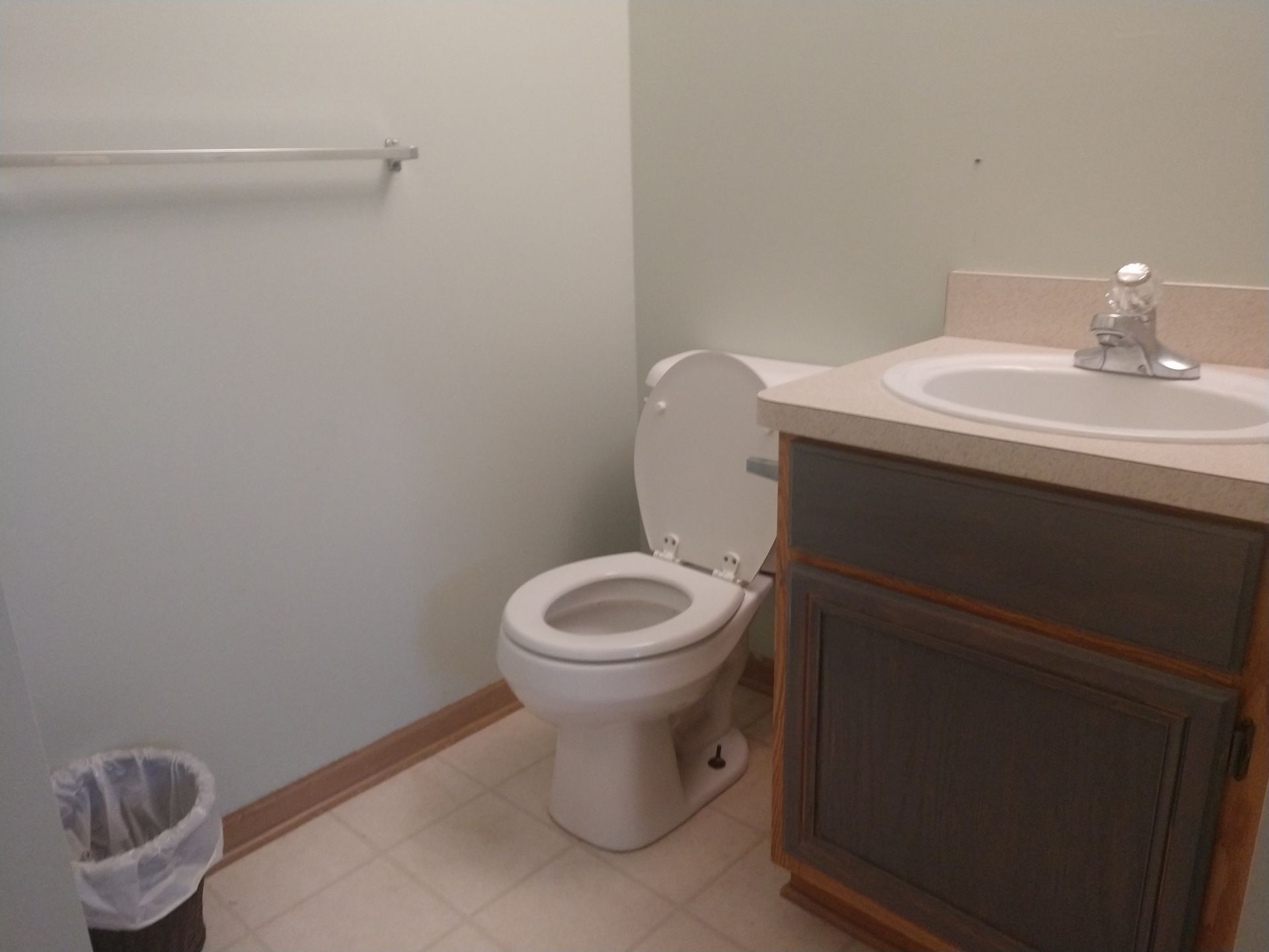 A bathroom with a toilet a sink and a trash can