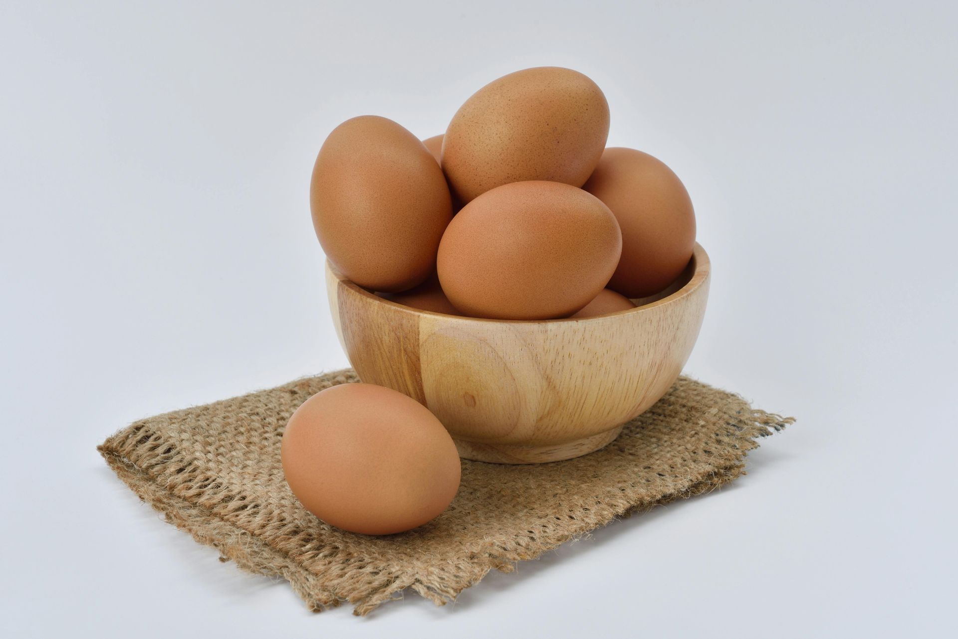 Hen sitting on eggs in a nest of dirt and plants.