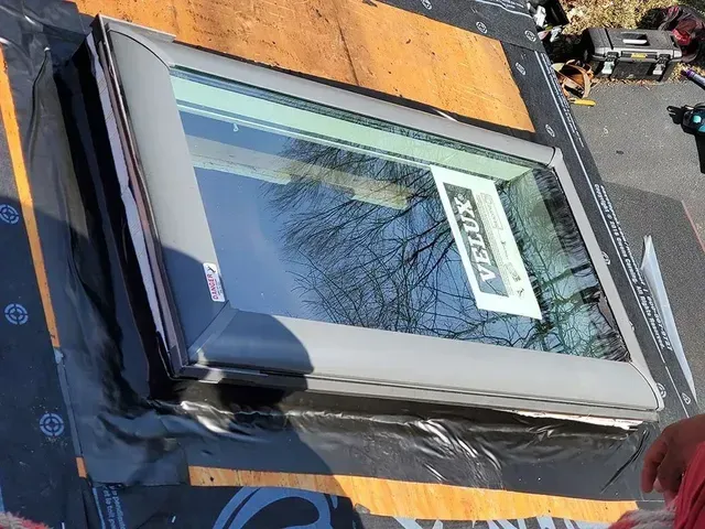 Skylight installation on a roof, with the Velux brand window in place over black underlayment.