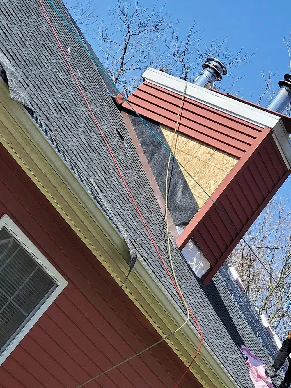 Red house roof with exposed plywood and chimney, under construction.
