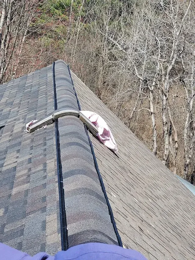 Roof with asphalt shingles and a bent metal flashing.