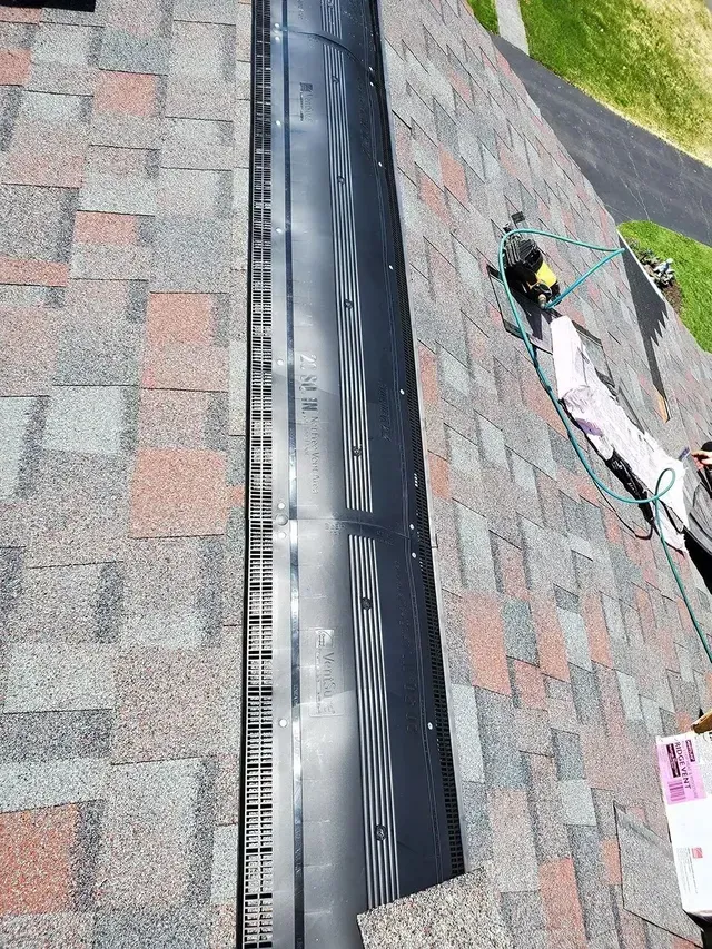 Black metal roof flashing installed between shingles.