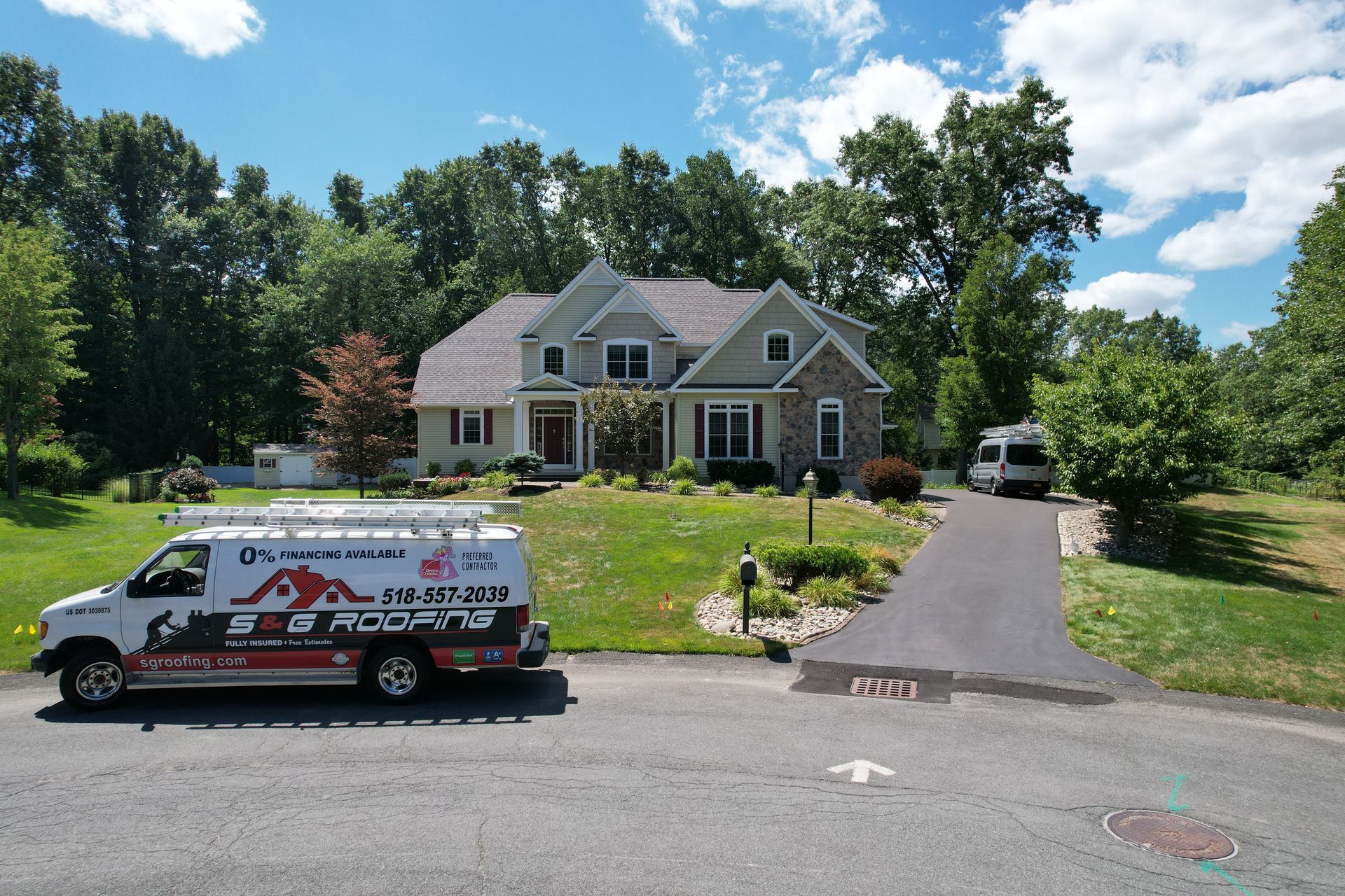 House with a van in the driveway; green lawn and trees.