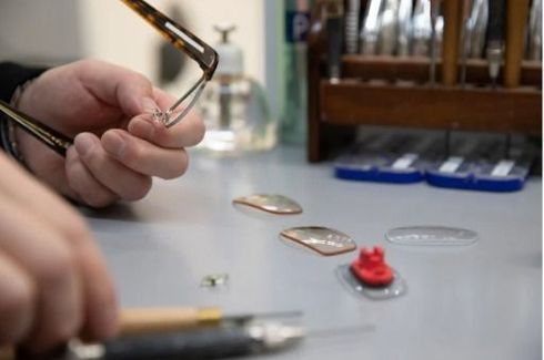 Occhiali da sole con montatura quadrata nera e lenti blu sfumate, su una superficie bianca, con una scatola con il marchio 