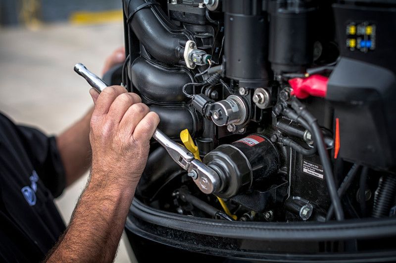 Mechanic using a wrench on a boat engine, close-up shot.