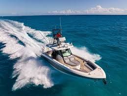 A motorboat speeds across the turquoise ocean, creating a large wake. A person is visible on the upper deck.