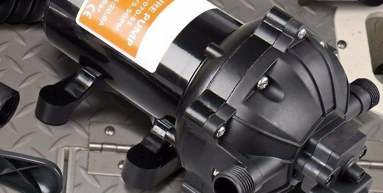 Black water pump on a metal surface with various objects in the background. The pump has an orange and white label.
