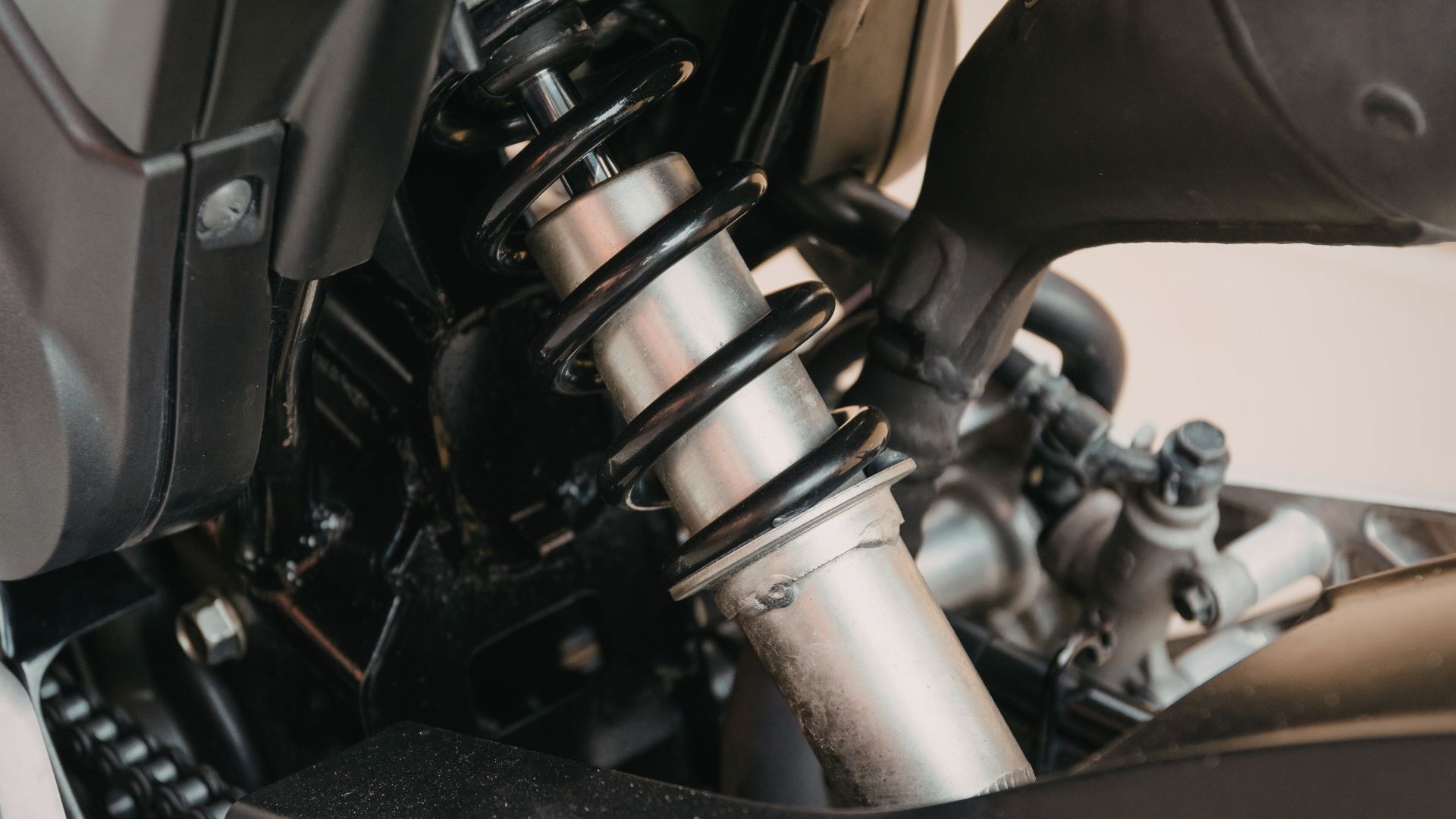Motorcycle rear shock absorber with black spring and silver cylinder.