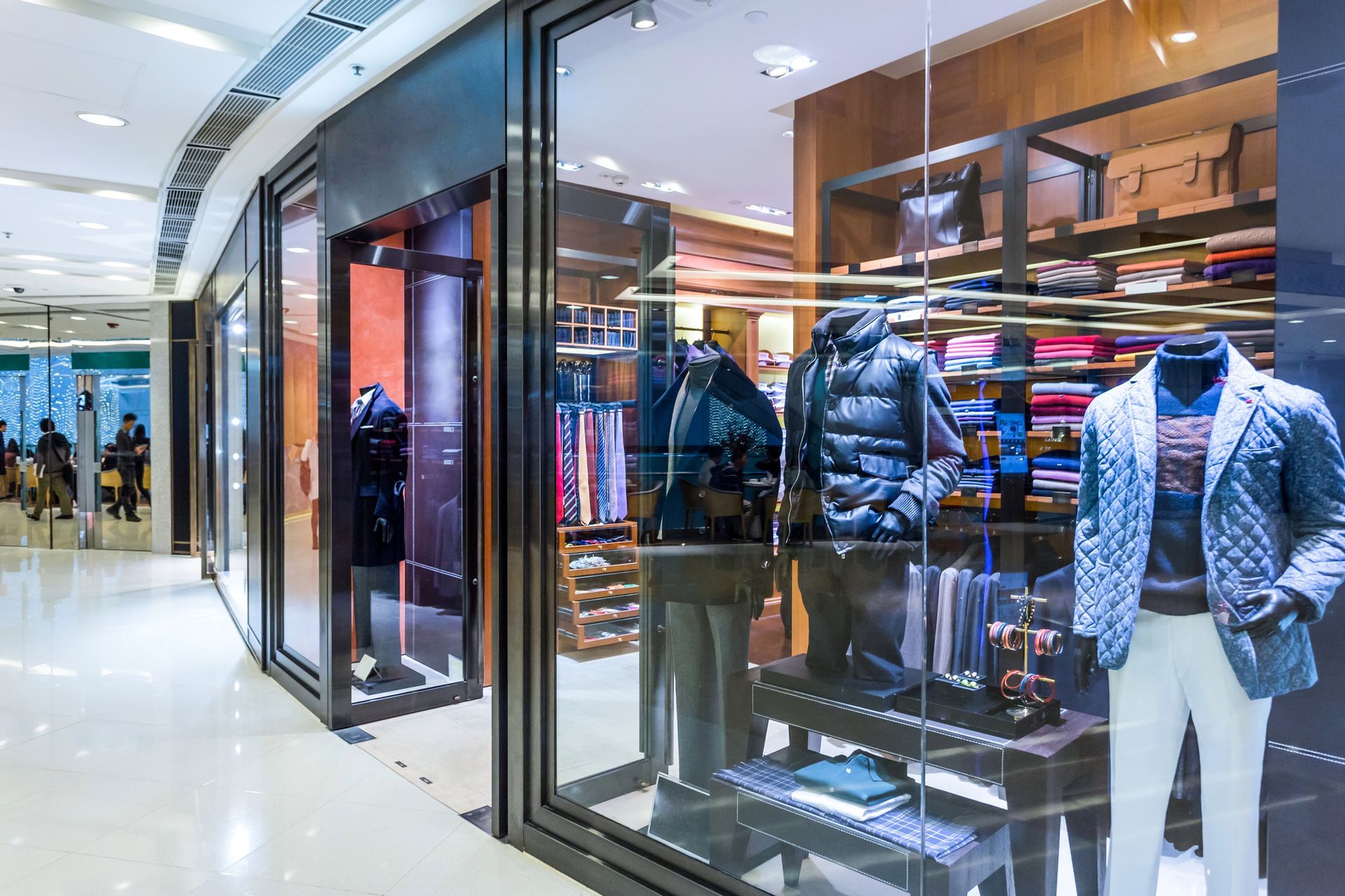 Vetrina di un negozio di abbigliamento maschile in un centro commerciale con manichini in abiti invernali.