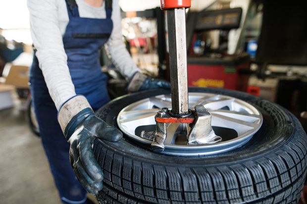 Mechanic mounting a car tire on a wheel rim with a tire-changing machine