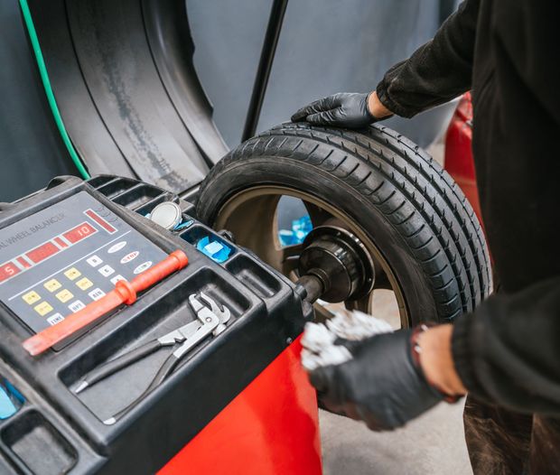 Mechanic balancing a tire on a red tire machine in a workshop