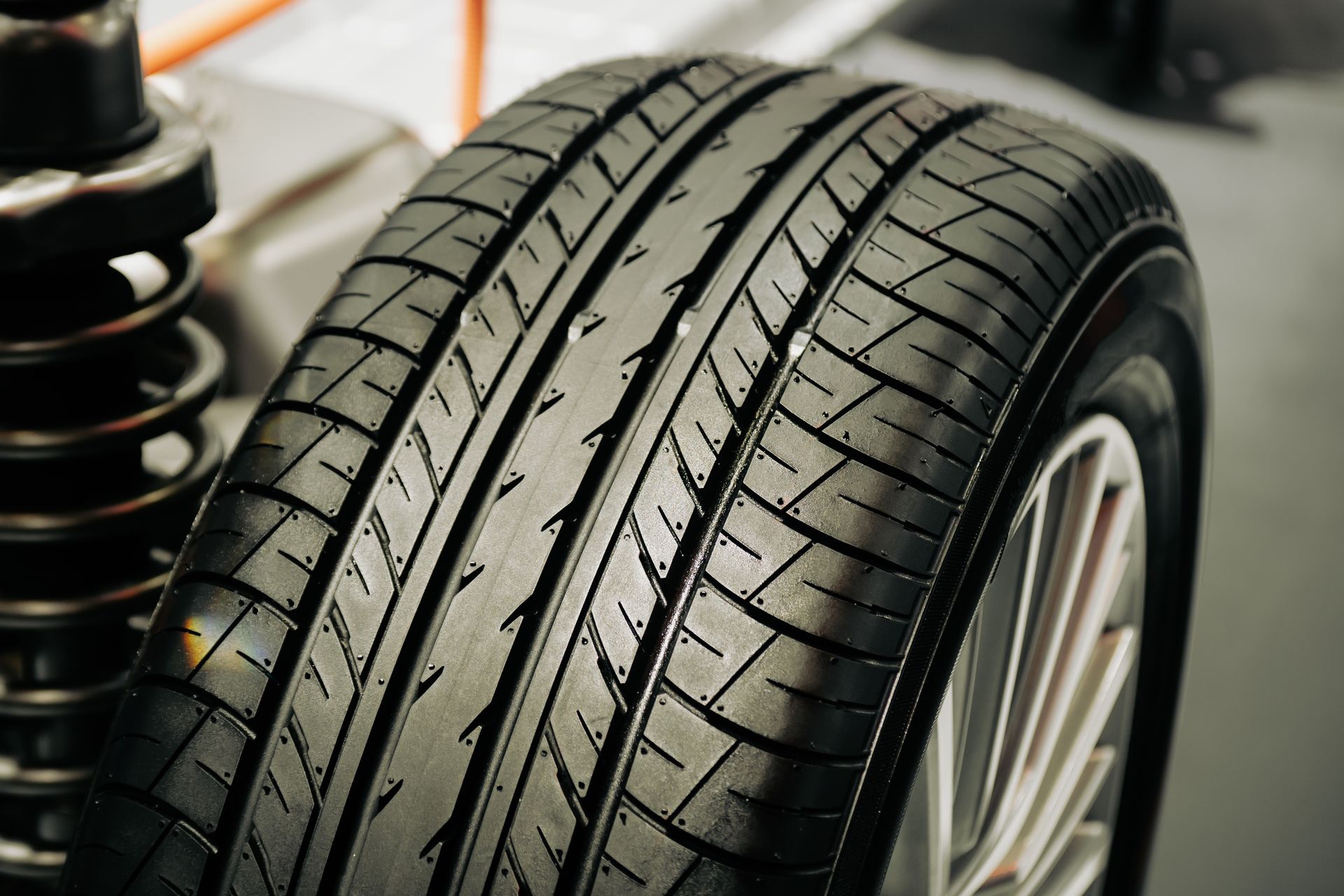 Close-up of a car tire with deep tread beside a suspension spring