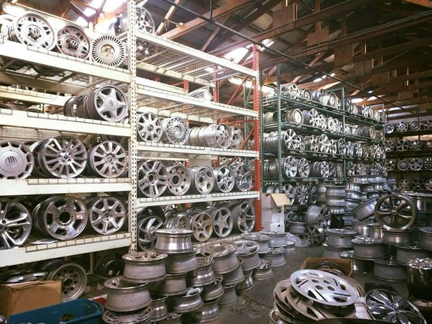 Warehouse filled with stacked metal rims and wheels on shelves and the floor