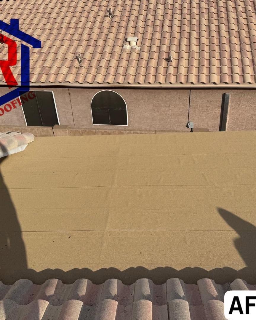 Rooftops with terracotta tiles and a beige wall under bright sunlight, with a shadow in the foreground
