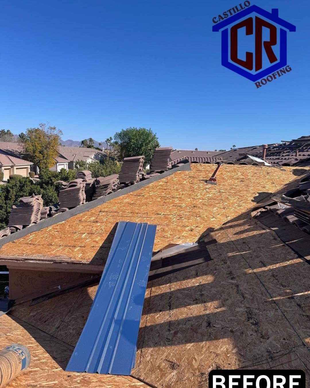 Roofer’s before photo of damaged roof under blue sky, with exposed underlayment and debris.