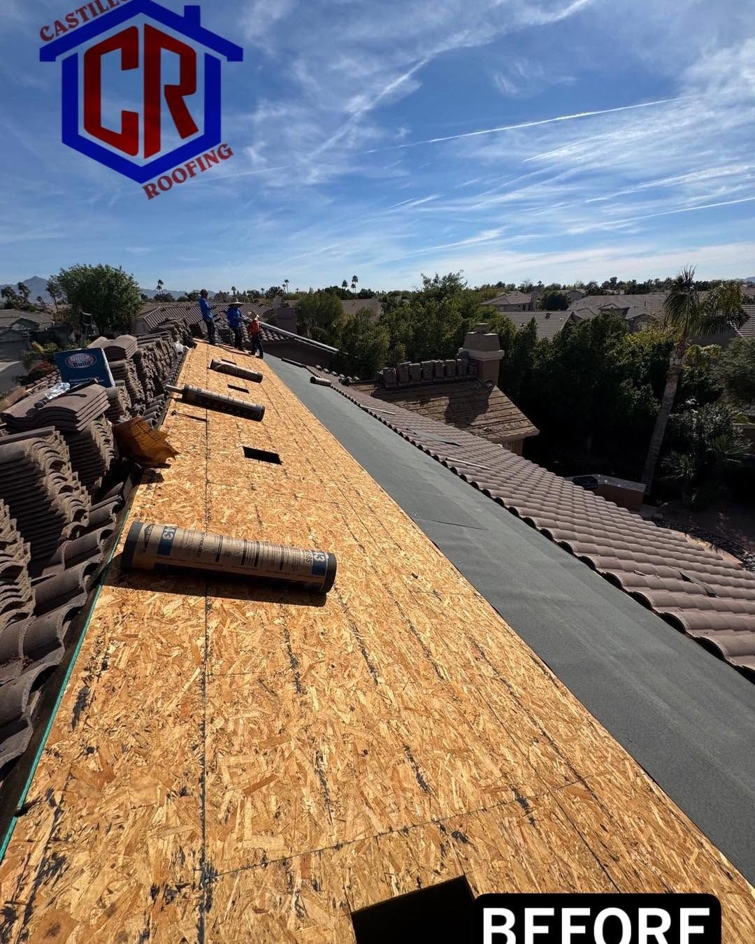 Rooftop underlayment installation in progress, with rolled roofing on a sloped roof under a blue sky.