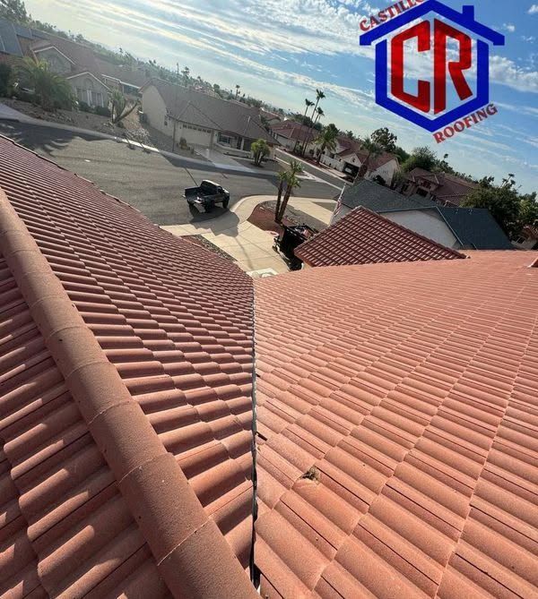 Red tile roof view over suburban neighborhood under a blue sky, with a CR Roofing logo.