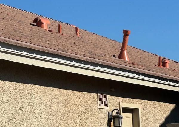 House roof with red vents and a chimney against a blue sky