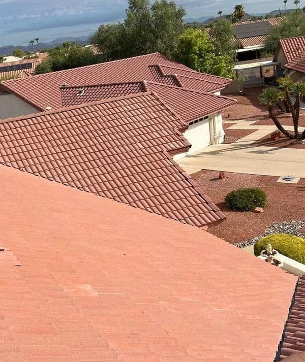 Red-tiled rooftops in a suburban neighborhood with a driveway and landscaped yard.