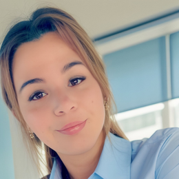 Woman with light brown hair, smiling, wearing a light blue shirt.