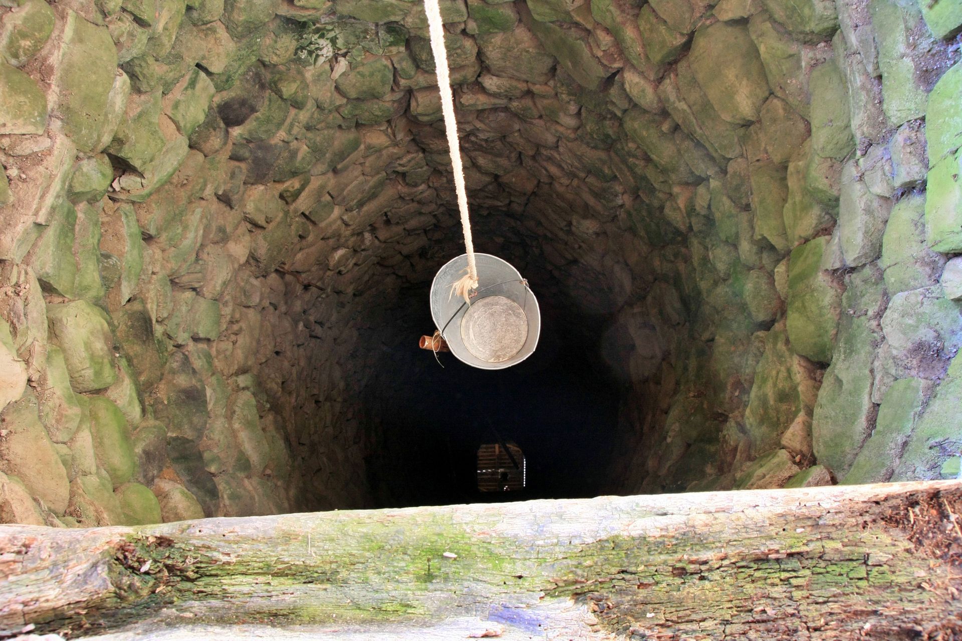 A bucket is hanging from a rope in a stone well.