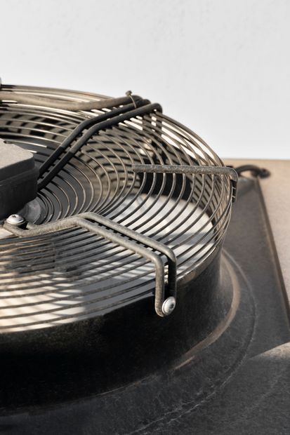 Coiled metal heating element with black wires on a dark appliance base