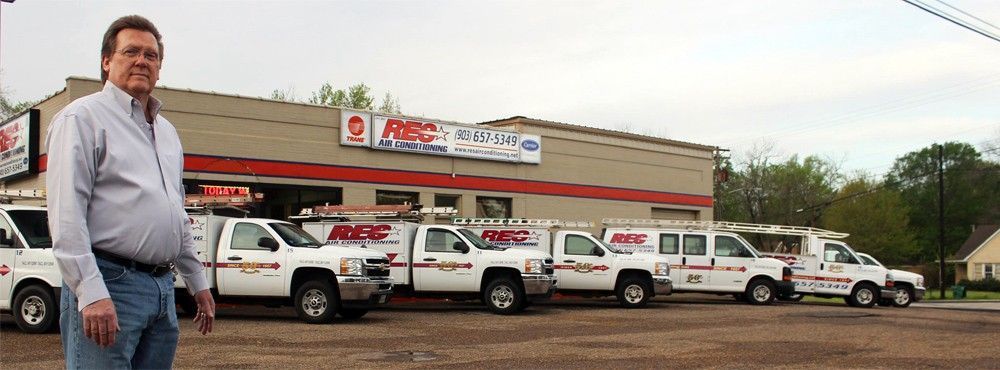 Man standing outside a business with a row of white service vans parked in front